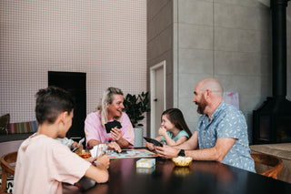 Parents and two kids playing The Golden Sausage Card Game on the play mat at the kitchen table